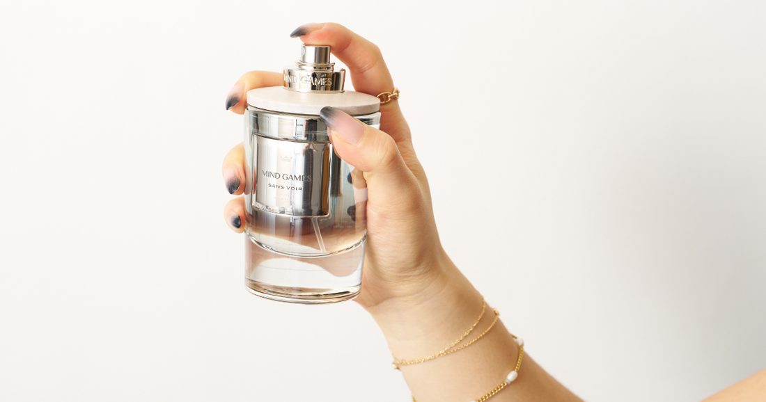A woman holding a bottle of Mind Games perfume.