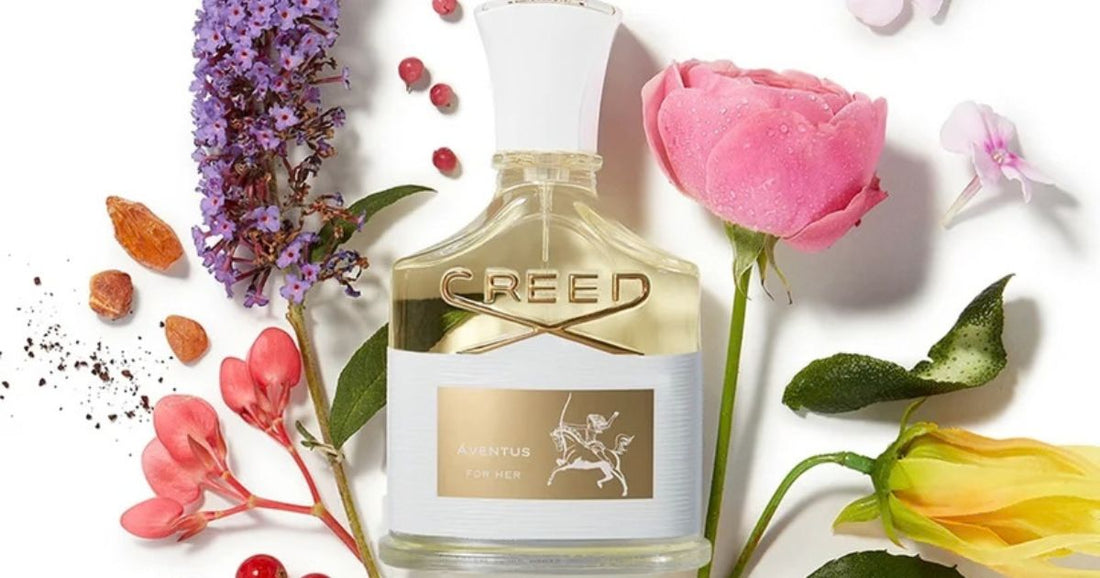 Creed for Her fragrance surrounded by flowers against a white background.