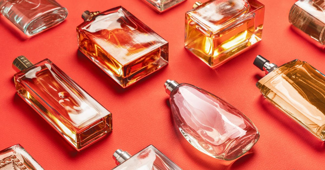 Various fragrance bottles of different notes laying on their side against a deep orange background.