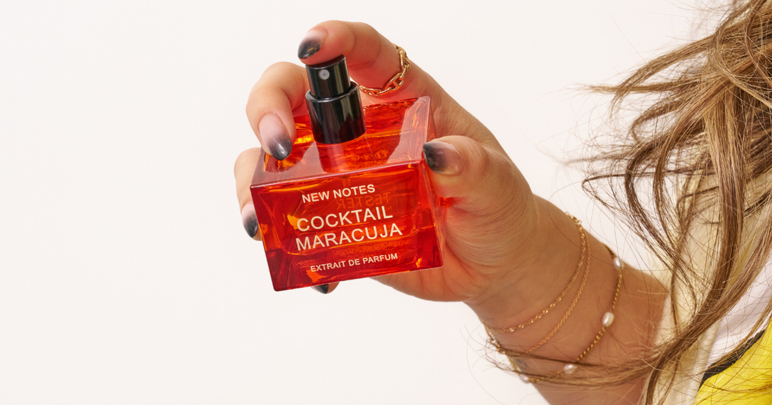 A woman holding a bottle of NEW NOTES  Cocktail perfume.