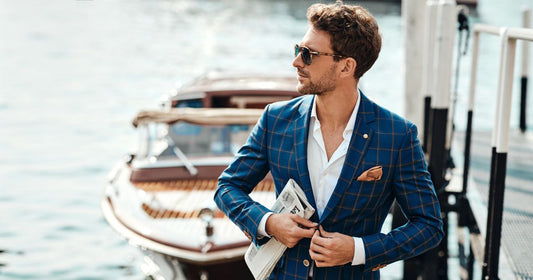 A man wearing a blue suit looking like a celebrity while steppping off a boat.