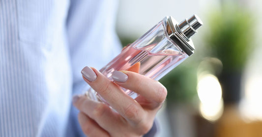 A woman's hand holding a bottle of fragrance every woman should have.