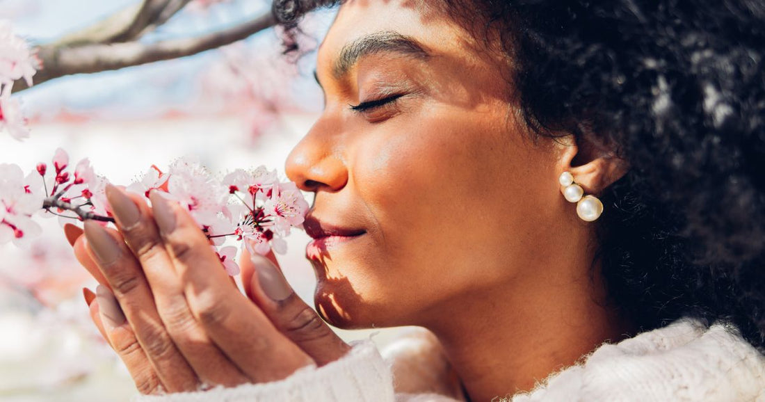 A beautiful women sniffing cherry blossoms.