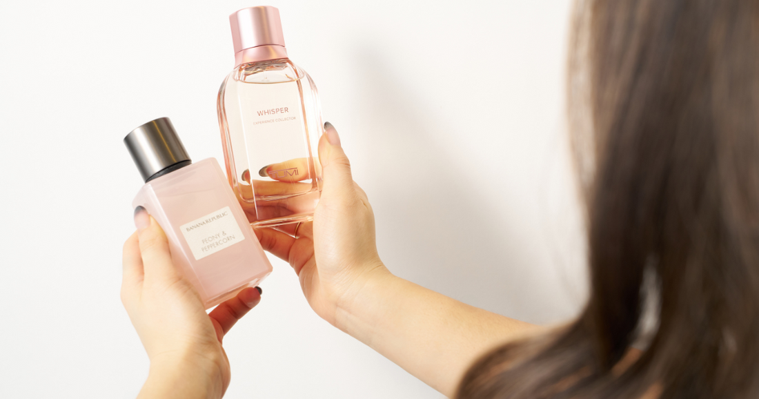 A woman looking at two perfumes to use for layering.