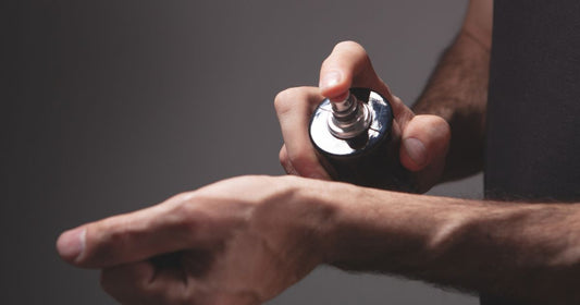 A man spraying a fragrance on his wrist.