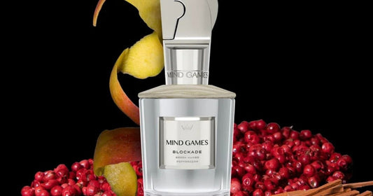 Mind Games Blockade fragrance against a black background surrounds by fruits.