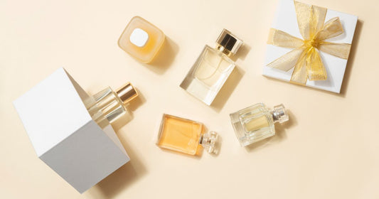 Several perfume bottles with a gift box on a light orange background.
